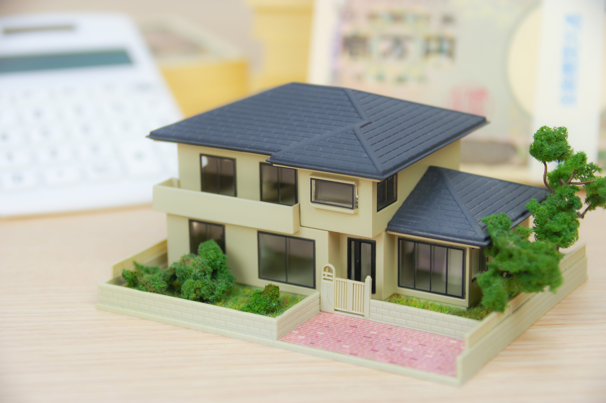 補助金申請に関連する戸建て模型と電卓、一万円札