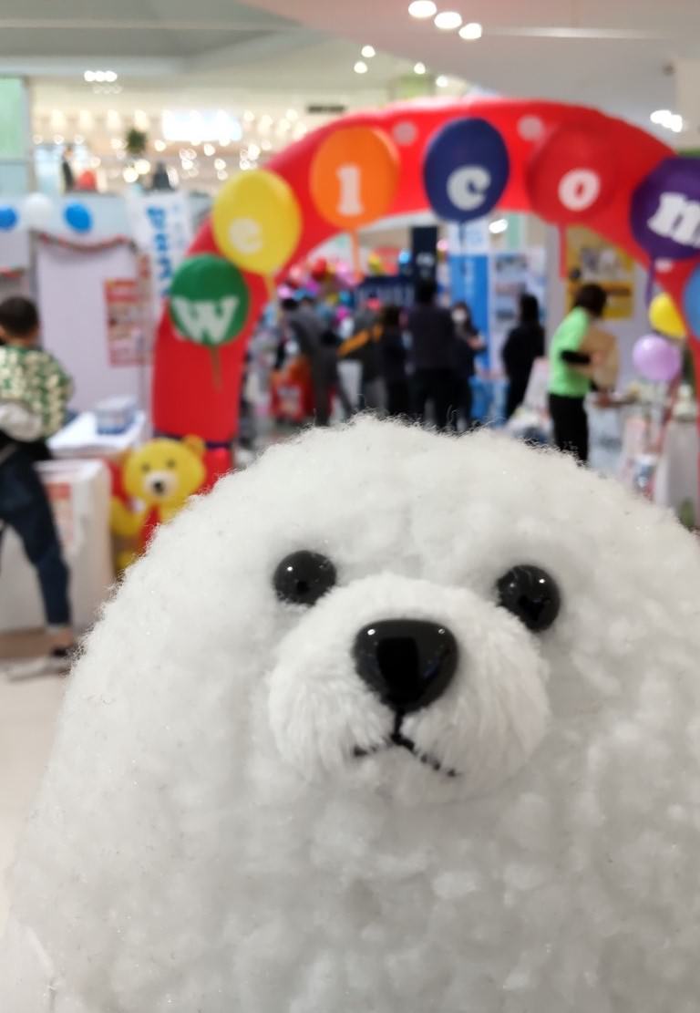 イベント会場で来場者に挨拶するイエティの顔のアップショット。ふわふわの毛並みが特徴的。