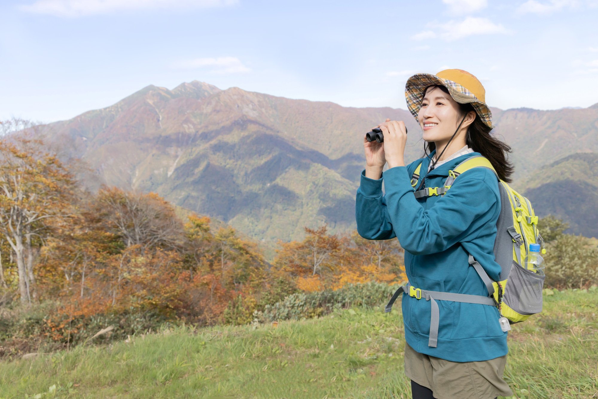 双眼鏡で遠くを見渡しながら土地を探す女性
