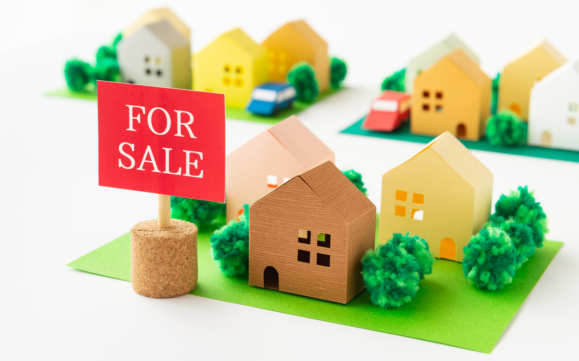 FOR SALEの看板が立つ住宅街のミニチュア。住宅売却時の売りやすさを表現