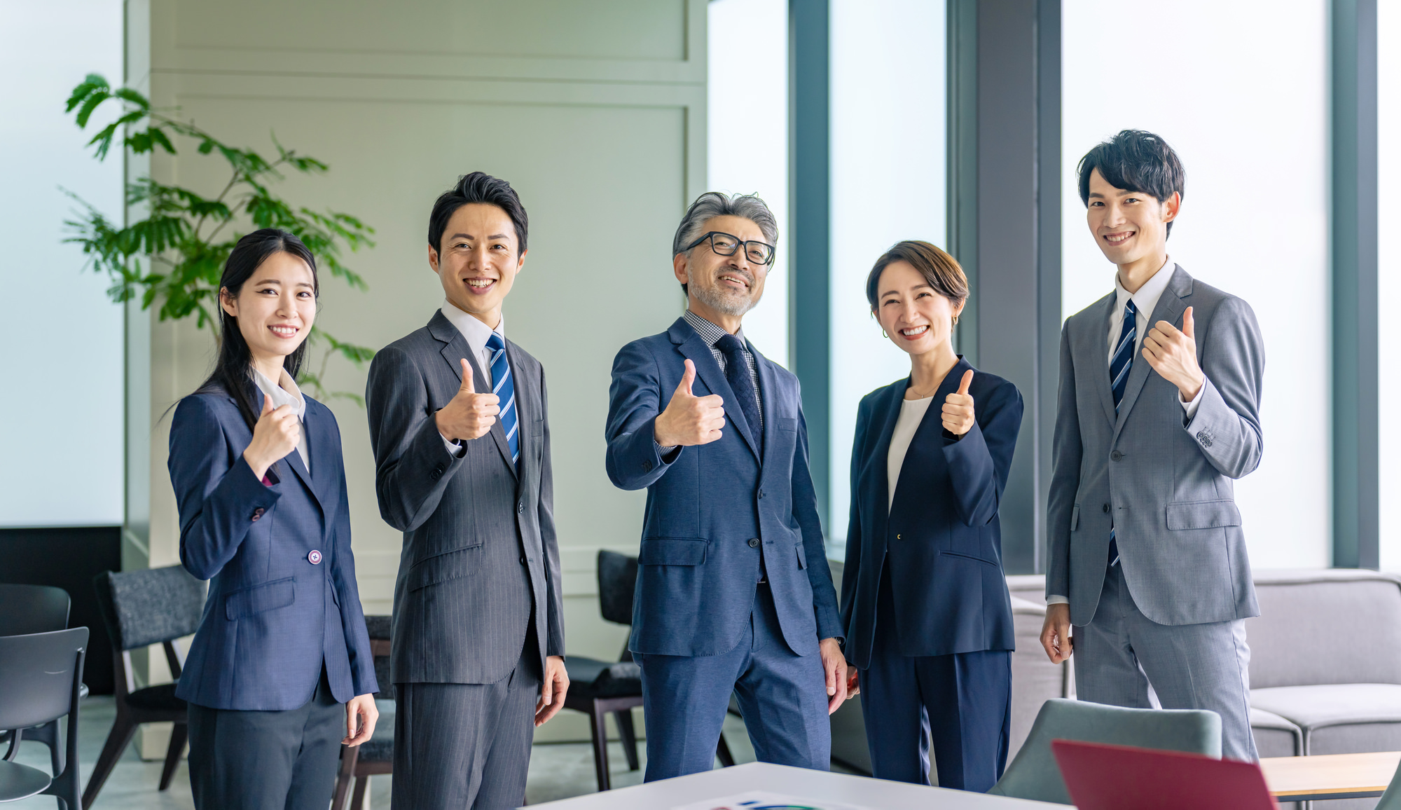 スーツ姿の住宅営業マンが整列し、笑顔でポーズ。しっかりしたバックアップ体制を示す